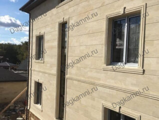 Боковой фасад дома с облицовкой из дагестанского камня и вертикальными декоративными элементами